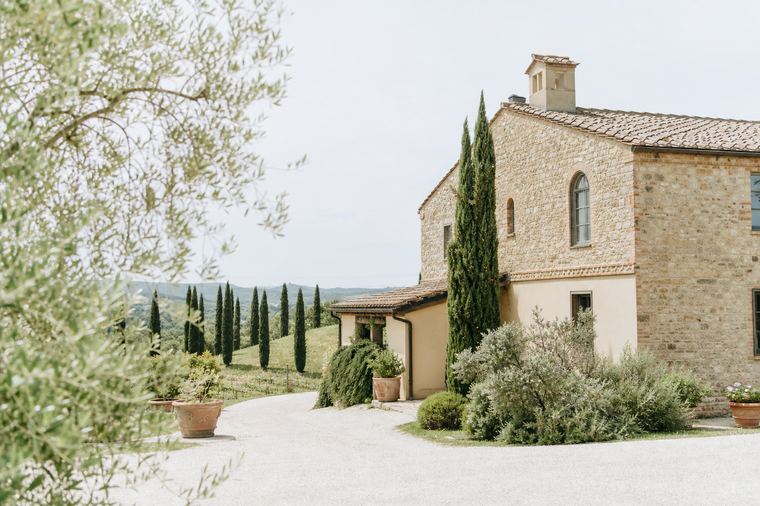 Casa colonica circondata da alberi vista dall'alto in una giornata serena.